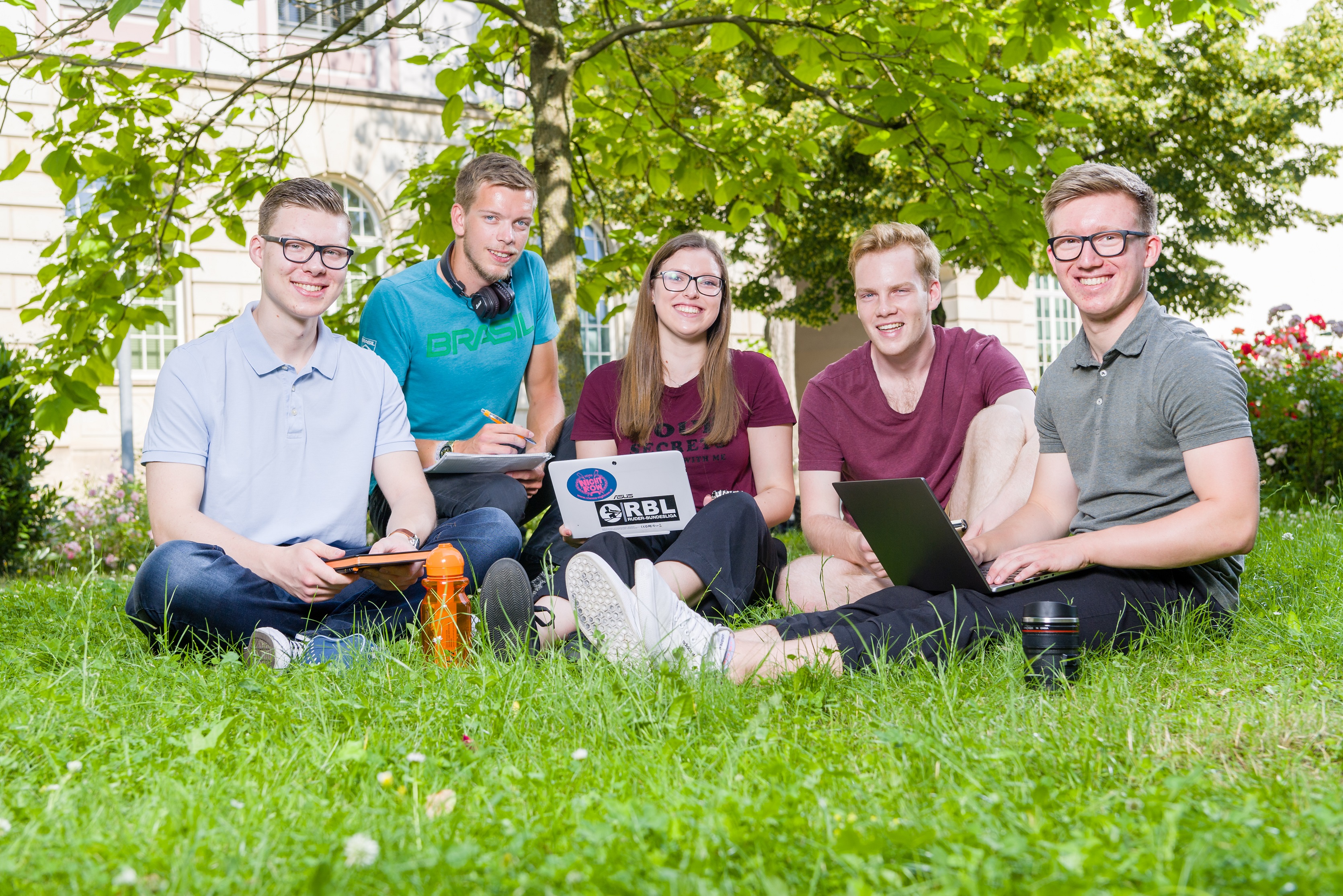 Studierende sitzen auf der Wiese