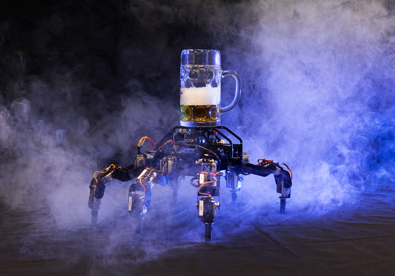 Ein sechsbeiniger Laufroboter transportiert ein Bierglas.