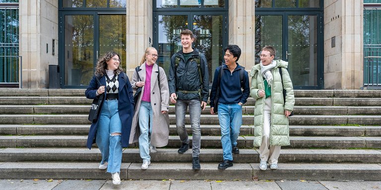 Studierende, die die Treppe des Hauptgebäudes hinunter laufen