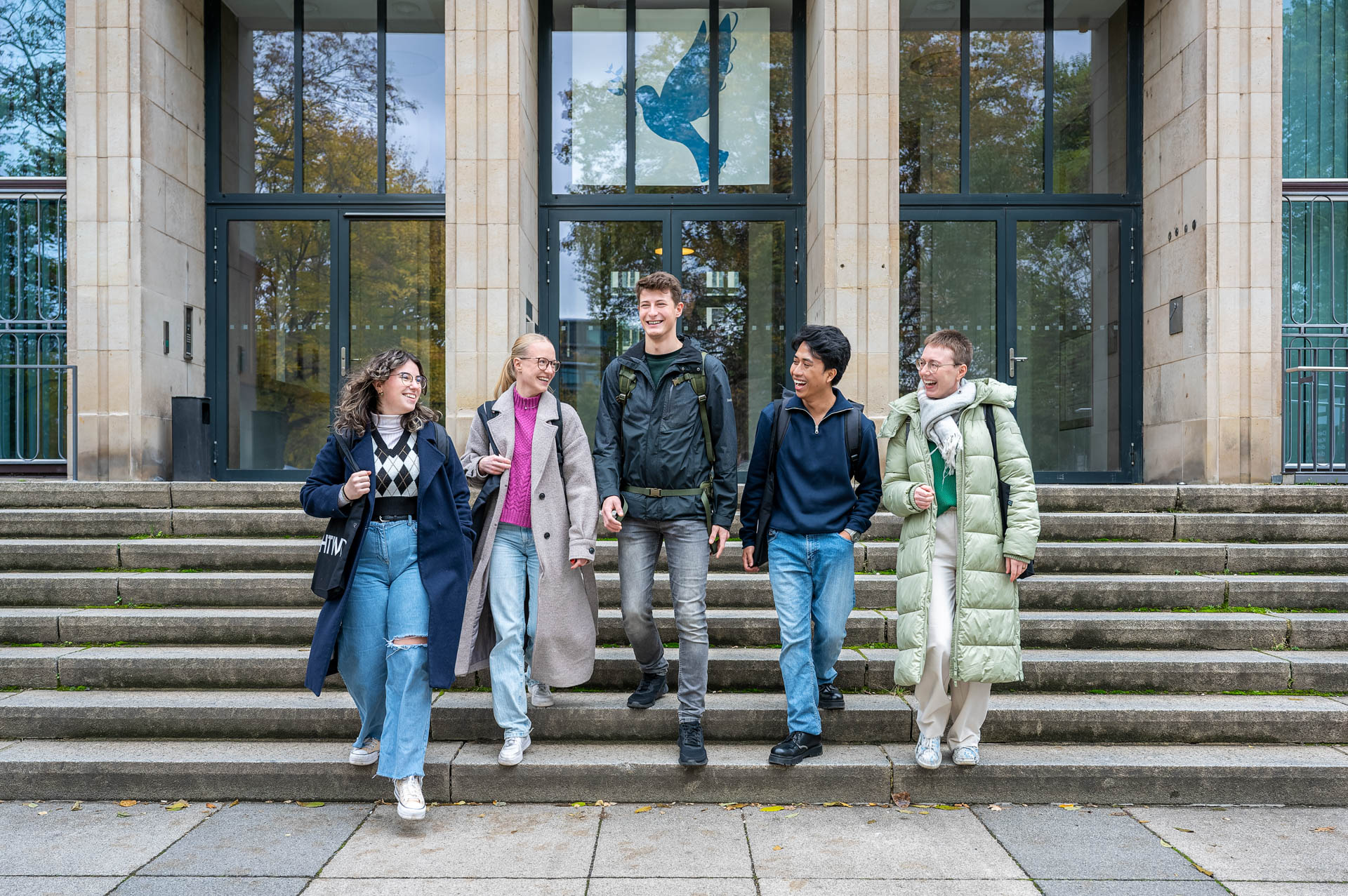 Studierende gehen vor dem Eingang zum Z-Gebäude die Treppe hinunter