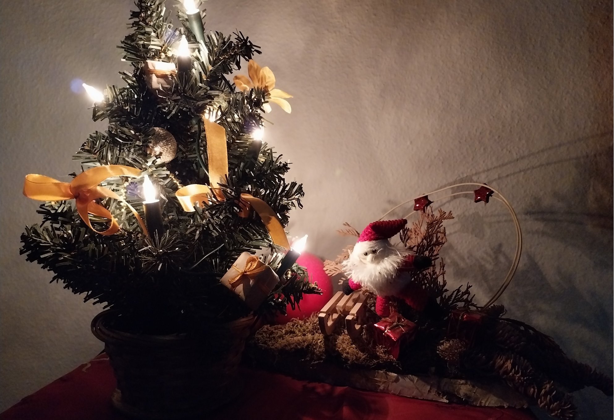 Weihnachtsdeko (kleiner beleuchteter Baum neben Weihnachtsmann)