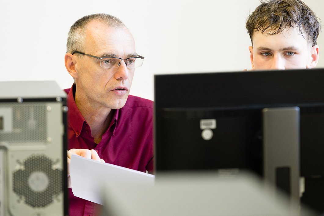 Zwei Männer im Gespräch vor dem Bildschirm eines PC