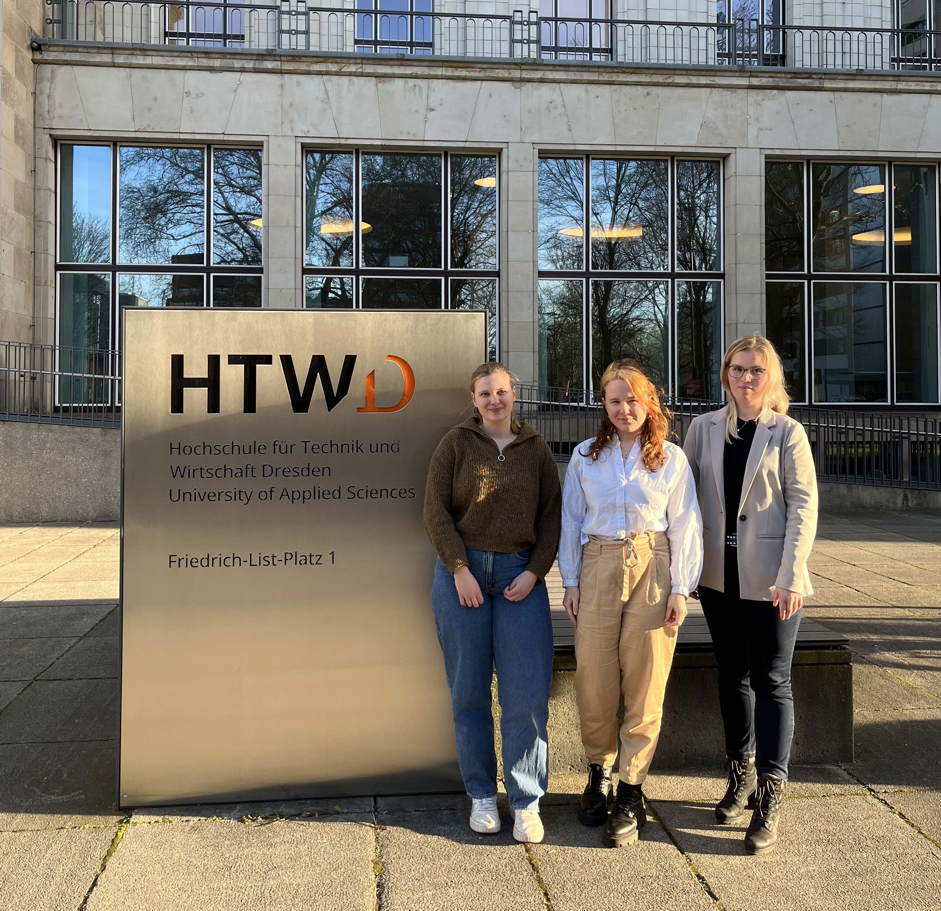 Das Bild zeigt drei Studentinnen vor dem HTWD-Gebäude